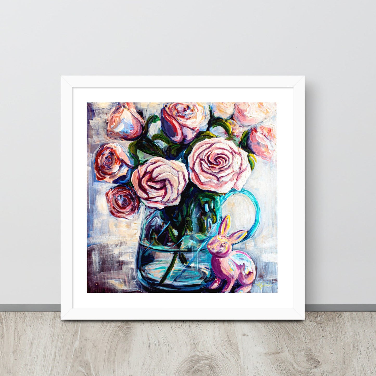 Product mockupA colorful painting of pink roses in a teal clear vase in a white frame leans against a wall