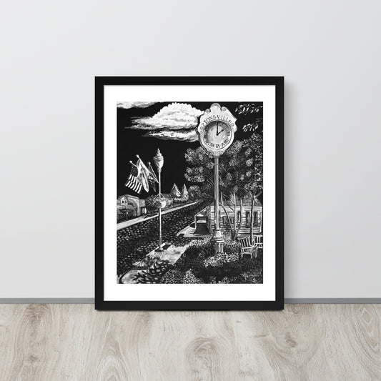 matte black and white framed art print of small town in black frame leaned up against gray wall on light toned wood floor