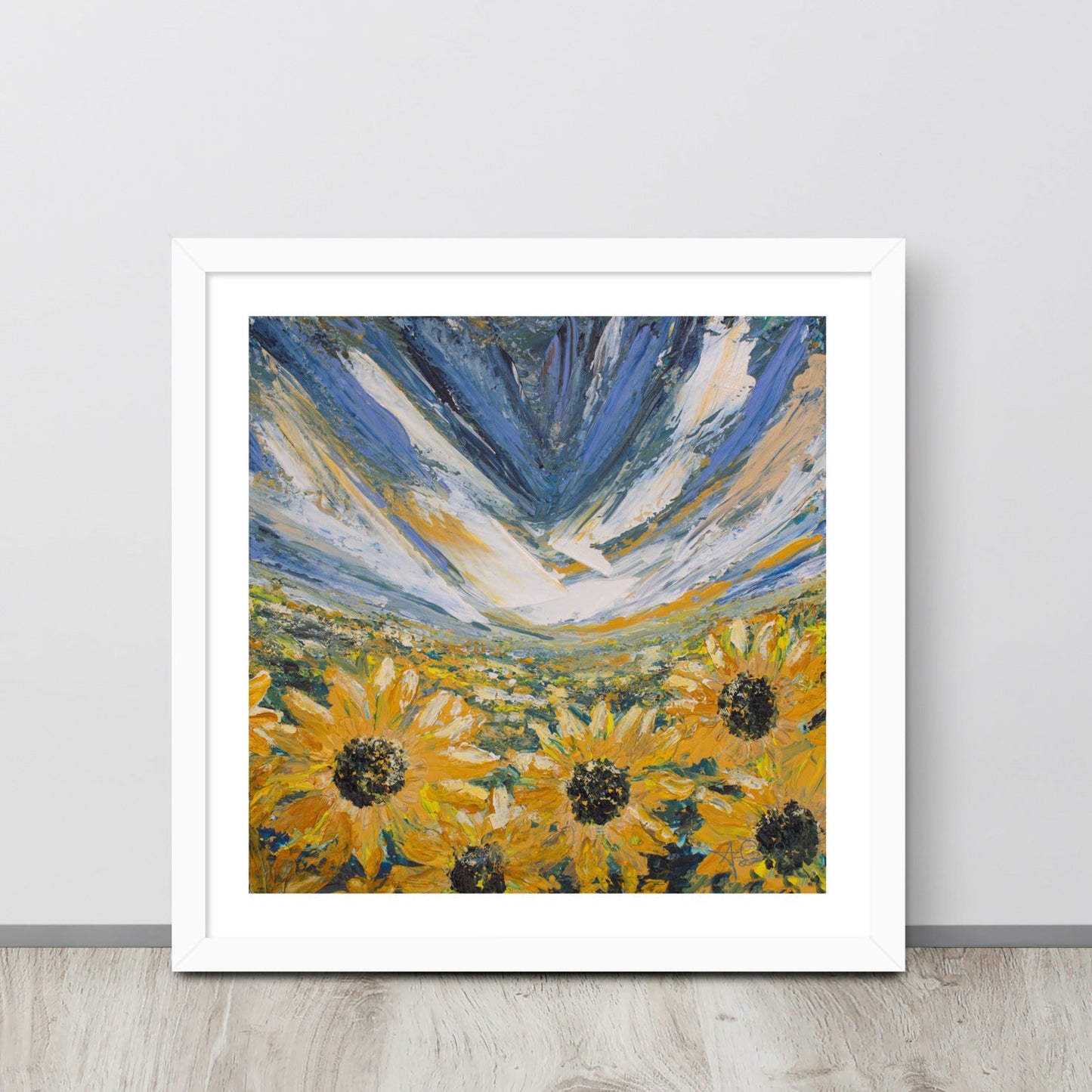 An abstract landscape sunflower field art print in a white frame leaned up against a wall