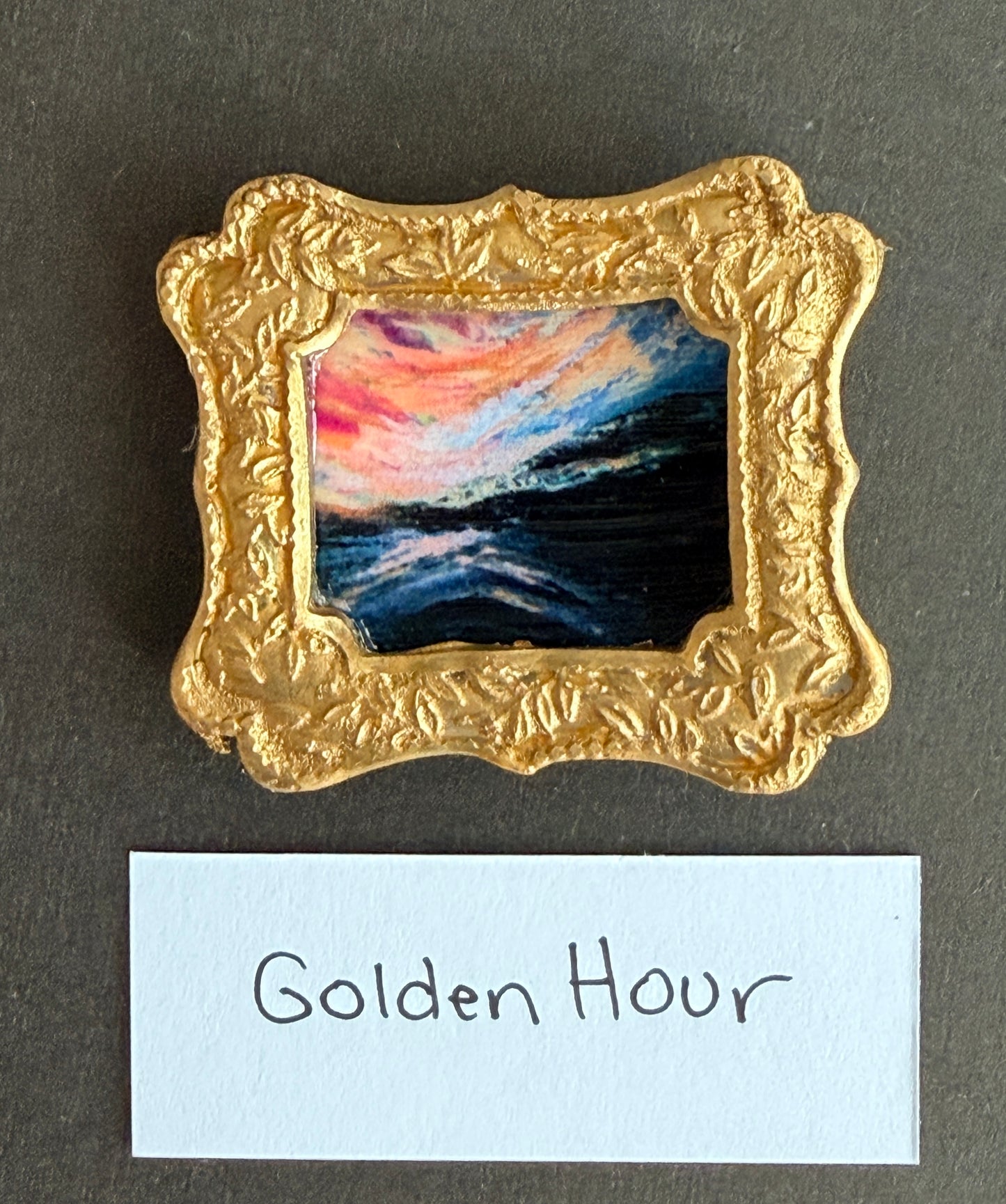 A vibrant sunset painting photo in a gold fridge magnet with the words Golden Hour below it