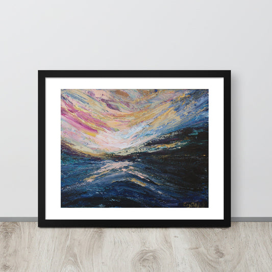 A colorful abstract landscape sunrise print in a black frame leaned up against a light colored wall