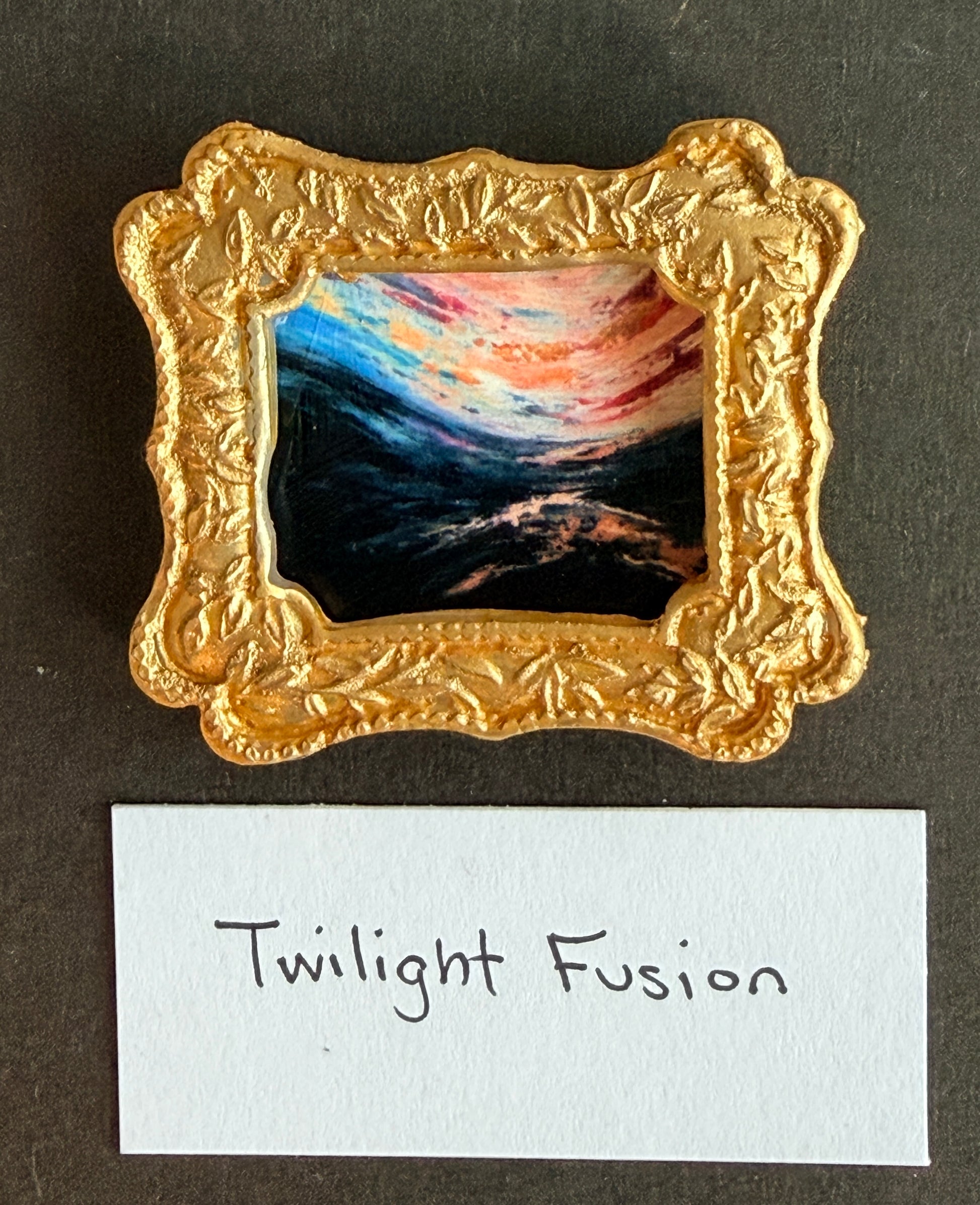 A vibrant abstract landscape piece of art in a small gold frame fridge magnet with the words Twilight Fusion below it