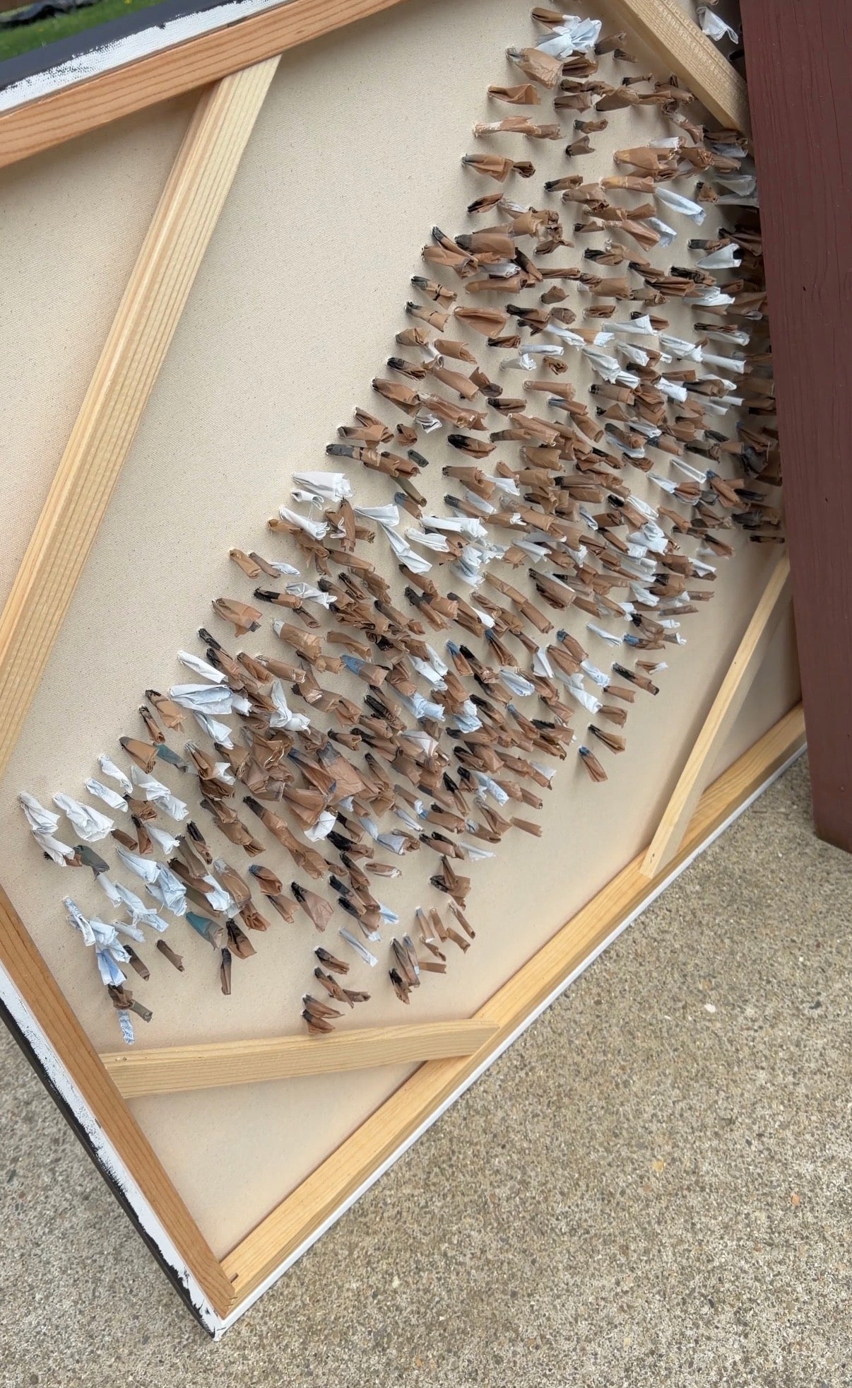 a large canvas is shown with multicolored pieces of rolled up plastic bag sticking out