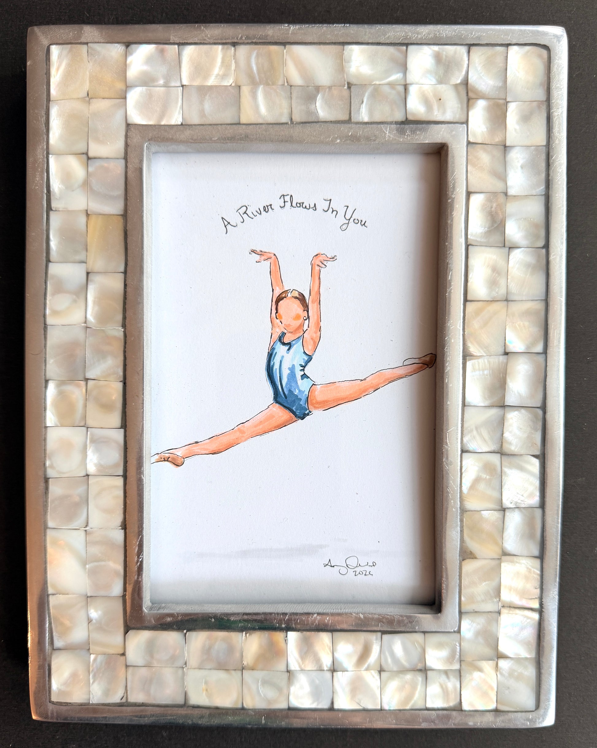 Framed artwork of a dancer in a shell frame on a dark background