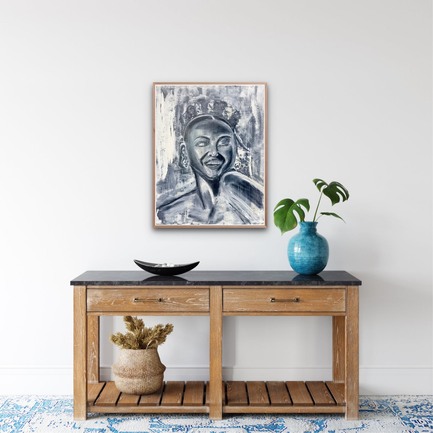 black and white portrait of a happy woman framed over and hanging on a wall above a decorated console table