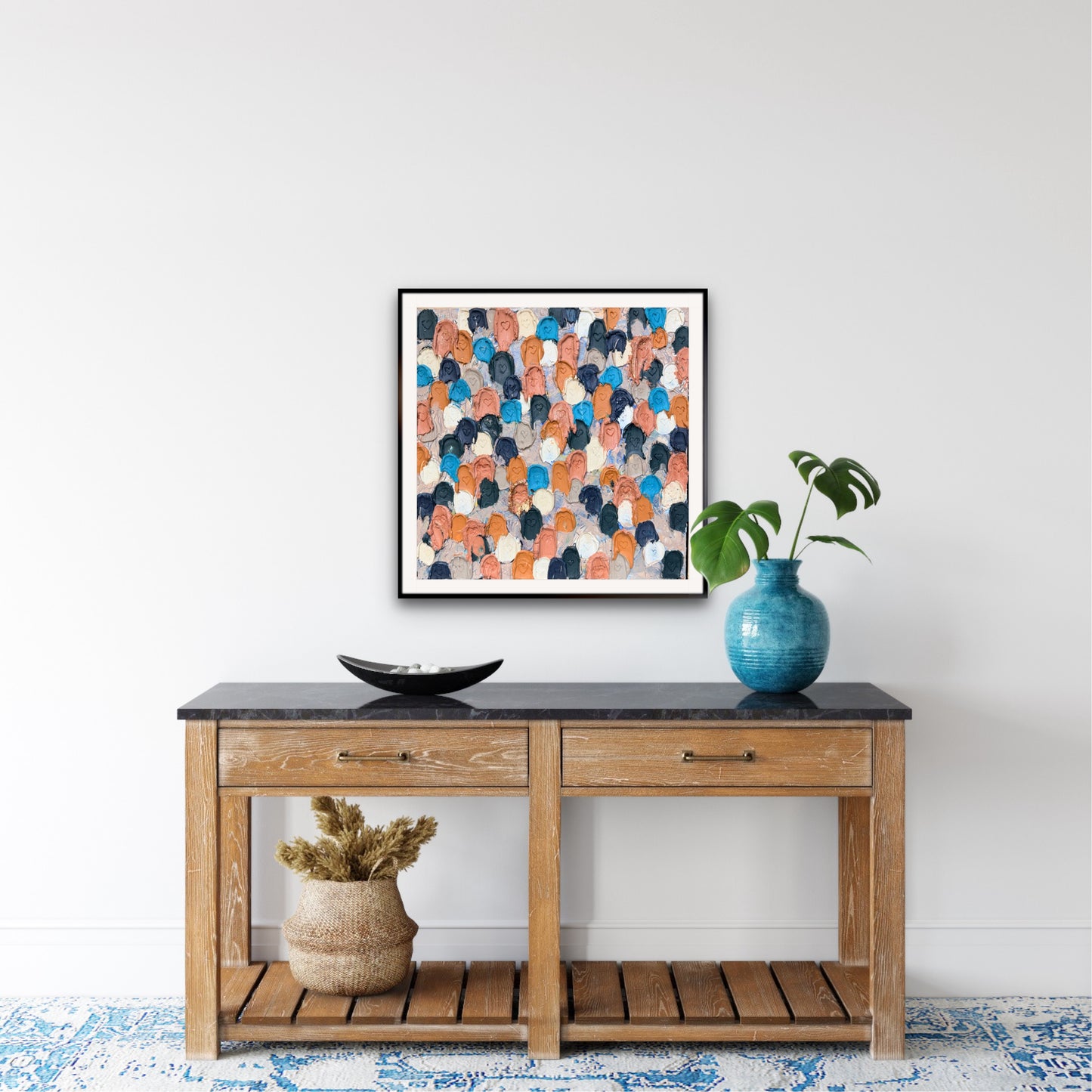 Wooden console table with decorative items including a vase, bowl, and abstract art on a white wall.