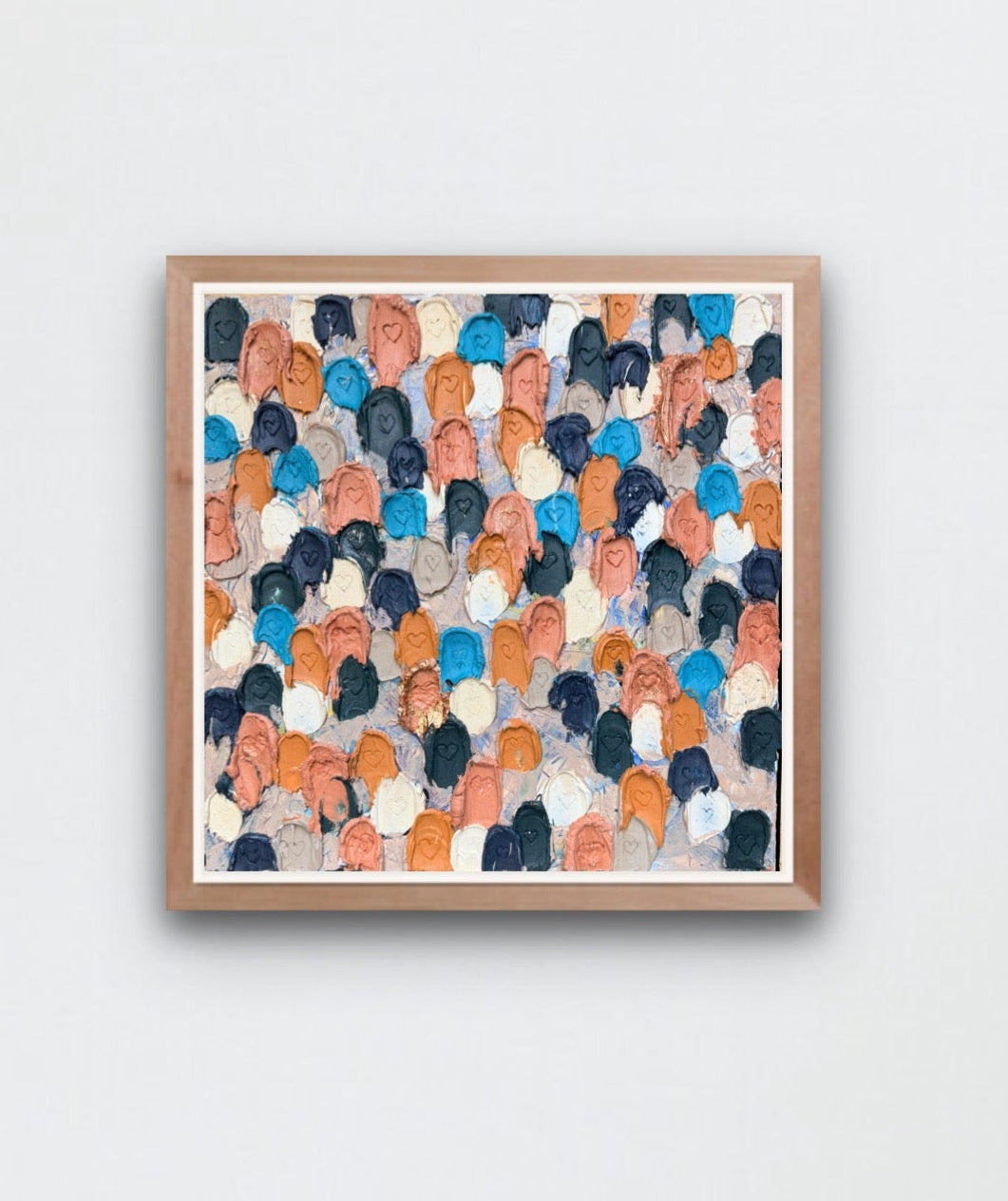 Modern interior with a colorful abstract painting close up of heavily textured painting of dollops of navy, cream, rose gold, and raw sienna with heart carved in them on a white wall.