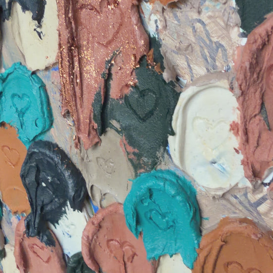 close up of heavily textured painting of dollops of navy, cream, rose gold, and raw sienna with heart carved in them