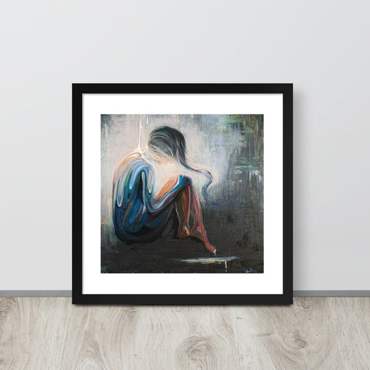 An art print of an abstract woman is framed in a black frame and sitting up against a gray wall on a neutral wood floor