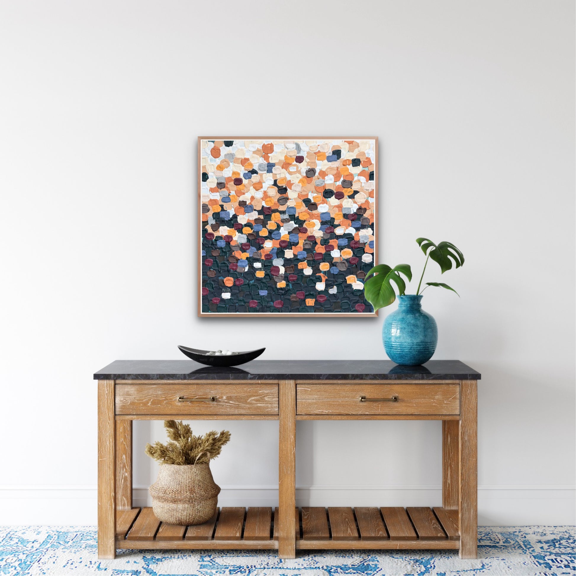 Wooden console table with decorative items and a colorful abstract painting on a white wall.