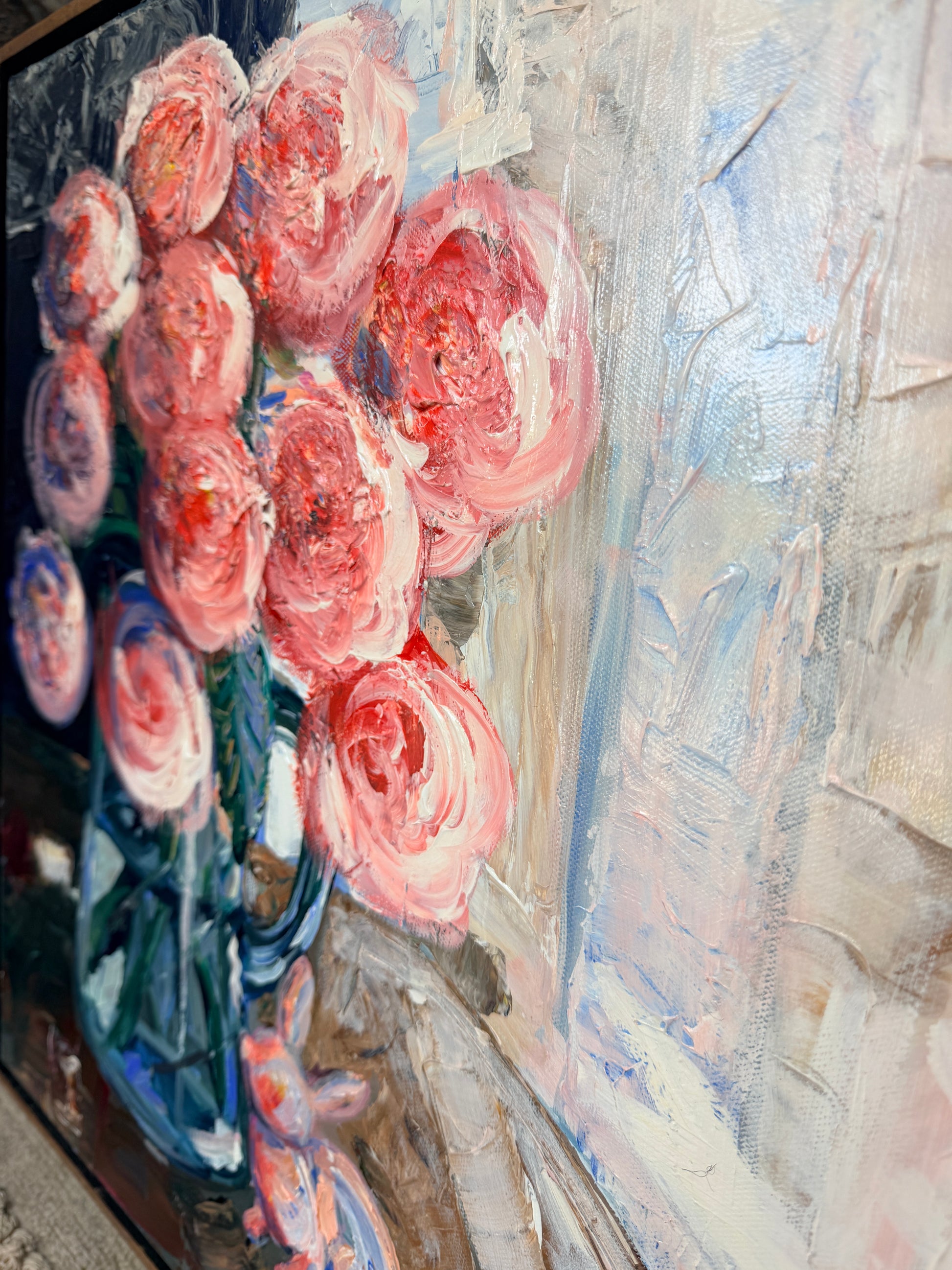 Painting of pink flowers in a blue vase with a glass figurine bunny in front on a textured surface